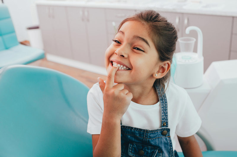 Kind zeigt auf Zähne